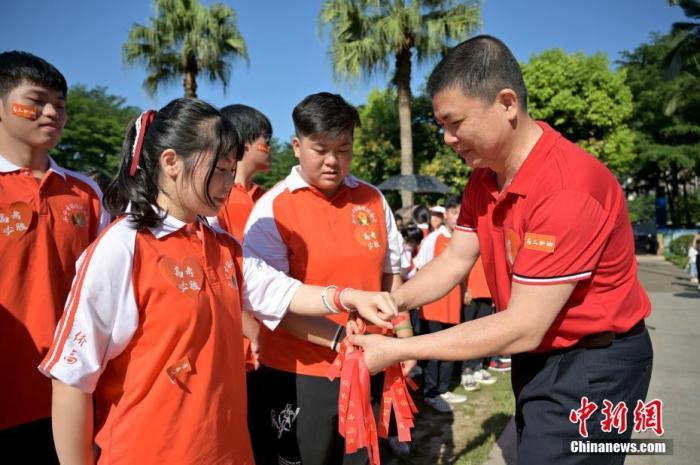 資料圖：廣西華僑實驗高中的教師為高三學(xué)子系上紅絲帶，盼望學(xué)子高考必勝。 俞靖 攝